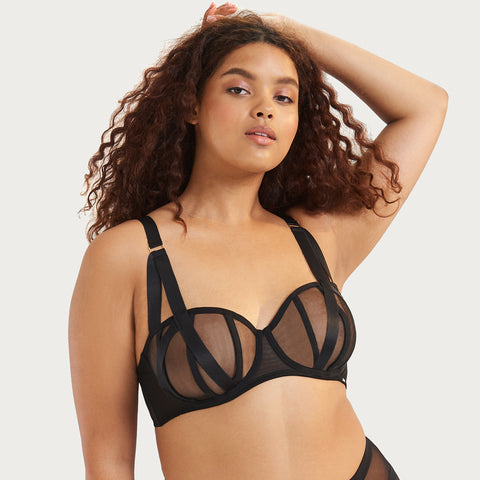 Model wearing the Karolina black balcony bra that exhibits a bondage inspired look with its adjustable shoulder straps and black mesh detail.
